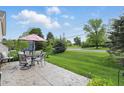 View of the backyard patio with dining set, overlooking the lush green lawn at 1663 Sweetgum Dr, Greenwood, IN 46143