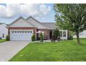 Charming brick and siding home features a well-manicured lawn and a two-car garage at 1663 Sweetgum Dr, Greenwood, IN 46143
