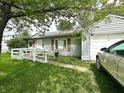 View of front of home with a white picket fence, ramp, muted red shutters and an attached garage at 2337 N Webster N Ave, Indianapolis, IN 46219