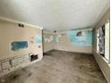 A damaged living room featuring bare floors, damaged walls, and a single window letting in natural light at 2337 N Webster N Ave, Indianapolis, IN 46219