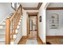 Inviting entryway with hardwood floors, staircase, and wooden trim leading to the kitchen at 329 W Hampton Dr, Indianapolis, IN 46208