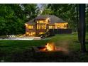 Backyard featuring a pool, fire pit and a beautifully lit exterior at dusk at 4128 Whitetail Woods Dr, Bargersville, IN 46106