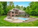Beautiful backyard with pool, patio, waterfall features, and lush green landscaping at 4128 Whitetail Woods Dr, Bargersville, IN 46106