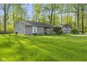 Lawn view of a quaint single-story home surrounded by lush greenery and mature shade trees at 5039 Five Points Rd, Indianapolis, IN 46239