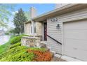 Inviting townhome entrance with stone accents, a red door, and well-manicured landscaping at 582 Conner Creek Dr, Fishers, IN 46038