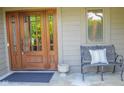 Inviting front porch with a wooden door, a bench, and a decorative pillow at 5851 Beisinger Pl, Indianapolis, IN 46237
