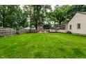 Spacious backyard with lush green grass, wooden fence, shed and a firepit surrounded by chairs at 6137 Evanston Ave, Indianapolis, IN 46220