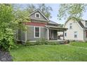 Classic home featuring a covered porch and well-maintained lawn with mature trees at 6159 Broadway St, Indianapolis, IN 46220