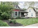 View of a quaint home with a well-manicured lawn and inviting front porch swing at 6159 Broadway St, Indianapolis, IN 46220