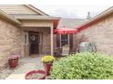 Inviting front porch area with a red umbrella, potted plants, and outdoor seating, perfect for relaxing at 6503 E Walton Dr, Camby, IN 46113