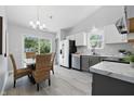 Modern kitchen with white cabinets, stainless steel appliances, and a dining area with wicker chairs at 6613 Apollo Way, Indianapolis, IN 46278