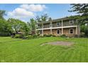 Spacious home with a large green lawn and mature trees on a sunny day at 6825 Farmleigh Dr, Indianapolis, IN 46220
