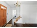 Inviting foyer with hardwood floors, staircase, chandelier, and painted entry door at 6825 Farmleigh Dr, Indianapolis, IN 46220