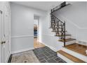 Inviting foyer with staircase, dark slate floors, white trim, and coat closet near the front door at 9860 Sunnymeade Ln, Indianapolis, IN 46280