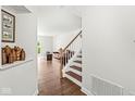 Inviting entryway featuring hardwood floors, staircase, and a glimpse into the living room with a leather sofa at 10143 Winslow Way, Fishers, IN 46037