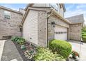 Exterior view of the house showcasing light brick accents, garden bed with flowers and an attached two-car garage at 10143 Winslow Way, Fishers, IN 46037