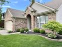 Landscaped front yard featuring a well-maintained lawn, shrubs, and decorative stone at 10305 Lakeland Dr, Fishers, IN 46037
