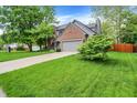 Home featuring a spacious green lawn, mature trees, brick accents, attached garage, and long driveway at 10310 Foxwood W Dr, Carmel, IN 46280