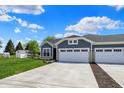 Inviting single-story home with a wide driveway, two-car garage, and lush green lawn under a blue sky at 1639 Clover Crossing Dr, Greenfield, IN 46140