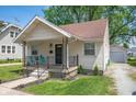 Inviting home with a quaint front porch, complemented by a detached garage and lush greenery at 1912 Broadway St, Anderson, IN 46012