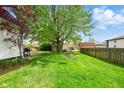 Spacious backyard with lush green grass, mature trees, wooden privacy fence, and a shed at 218 Pearl St, Fortville, IN 46040