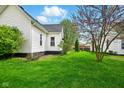 Side exterior view of a well-maintained house with lush green grass and healthy trees at 218 Pearl St, Fortville, IN 46040