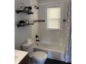 Bright bathroom with a combination shower/tub, updated fixtures, and floating shelves for storage at 3720 W 16Th St, Indianapolis, IN 46222