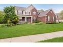 Charming two-story brick home featuring a welcoming front porch and lush green lawn at 3743 Earhart Dr, Carmel, IN 46074