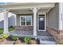 Covered front porch with brick accents, white columns, and view of the front yard and a partial view of the street at 6305 Norwich Dr, Brownsburg, IN 46112
