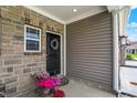 Welcoming front porch with a charming wreath, stone accents, and vibrant potted flowers at 6429 Yuma Ct, Whitestown, IN 46075