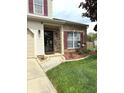 Inviting front entrance with brick accents, manicured landscaping, and a paved walkway and flower box at 6550 Spring Flower Dr, Indianapolis, IN 46237