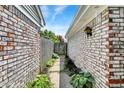 View down a narrow walkway between homes with brick siding, leading to a weathered wooden gate at 7642 Lancer Ln, Lawrence, IN 46226