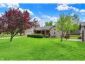 Beautiful ranch home with a well-manicured lawn, mature trees, and a welcoming covered porch at 7655 N Kitchen Rd, Mooresville, IN 46158