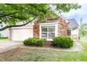 Charming brick home featuring a two-car garage, mature landscaping, and an inviting bay window at 7703 Park North Lake Dr, Indianapolis, IN 46260