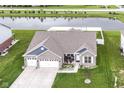 An aerial view of the brick home showing three-car garage, well-kept lawn, and a tranquil pond at 89 Kinnick Dr, Greenwood, IN 46143