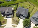 Aerial view of a home with a fenced backyard, lush green lawn, mature trees, and a driveway leading to a two-car garage at 11155 Funny Cide Dr, Noblesville, IN 46060