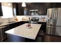 Modern kitchen featuring dark cabinetry, granite countertops, stainless steel appliances, and a center island with seating at 11155 Funny Cide Dr, Noblesville, IN 46060