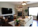 Cozy living room showcasing a stone fireplace, comfortable seating, a ceiling fan, and stylish decor at 11155 Funny Cide Dr, Noblesville, IN 46060