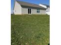 Expansive backyard with lush green grass, vinyl siding, and sliding glass door access to the house at 142 Winding Brook Way, Pendleton, IN 46064