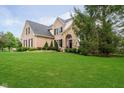 Attractive home featuring a well-manicured lawn, brick facade, stone accents, and mature trees at 14707 Thor Run Dr, Fishers, IN 46040