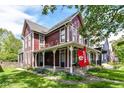 Two-story red home with a covered porch, green lawn, and an Indiana University flag on display at 1630 N New Jersey St, Indianapolis, IN 46202