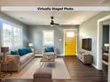 Virtually staged living room with modern furniture, wood floors, and a bright yellow door at 2009 Draper St, Indianapolis, IN 46203