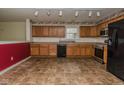 Open kitchen layout with oak cabinets, stainless steel appliances, and tile floors, adjacent to a red accent wall at 2416 Foxtail Dr, Plainfield, IN 46168