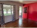 Inviting living room with a vibrant red accent wall and sun-drenched hardwood floors at 3528 Orchard Ave, Indianapolis, IN 46218
