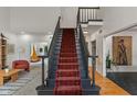 Grand staircase featuring a red carpet runner, elegant black banisters, and access to multiple living spaces at 4601 Fairhope Dr, Indianapolis, IN 46237