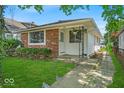 A charming ranch home with brick and white siding, adorned with greenery and a manicured lawn at 4956 W 11Th St, Speedway, IN 46224