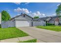 Exterior view of home showing a gray fence, attached garage, concrete driveway, and lush green lawn at 6707 Greendale Ln, Indianapolis, IN 46241