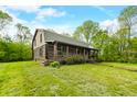 Classic log cabin with a covered porch, lush lawn, mature trees, and inviting curb appeal in a tranquil, wooded setting at 6968 S 300 W, Trafalgar, IN 46181