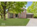 Charming brick home with a well-manicured lawn, mature trees, and attached two-car garage at 8300 Weaver Woods Pl, Fishers, IN 46038