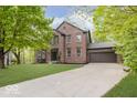 Charming brick home with a well-manicured lawn, mature trees, and attached two-car garage at 8300 Weaver Woods Pl, Fishers, IN 46038